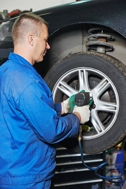 istock auto mechanic screwing car wheel by wrench 523182221