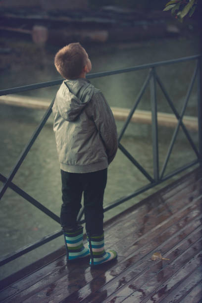 Boy standing in the rain on the deck looking up