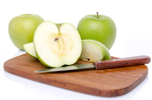 Ripe green apples with slices on a wooden cutting board, isolated on white