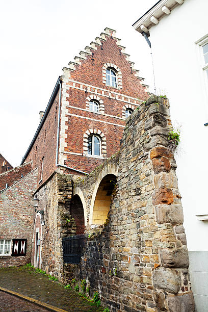 Part of old city wall Maastricht's between buildings. In background is brick building.
