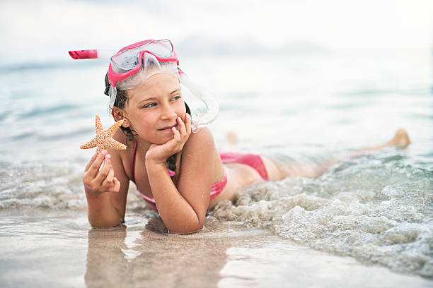 Little girl having fun snorkeling, holding a starfish.