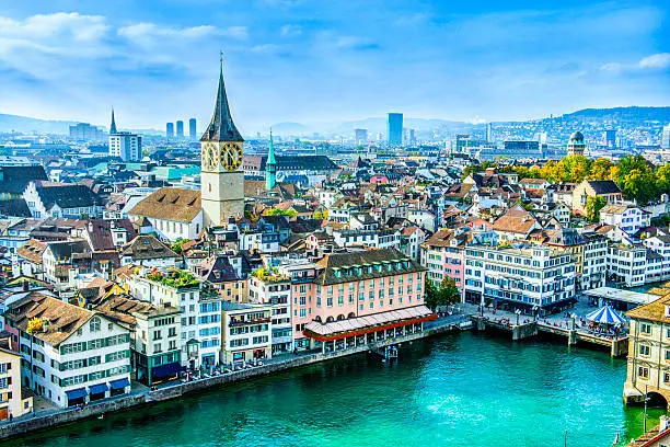 Aerial view of Zurich, Switzerland. Taken from a church tower overlooking the Limmat River. Beautiful blue sky with dramatic cloudscape over the city. Visible are many traditional Swiss houses, bridges and churches.