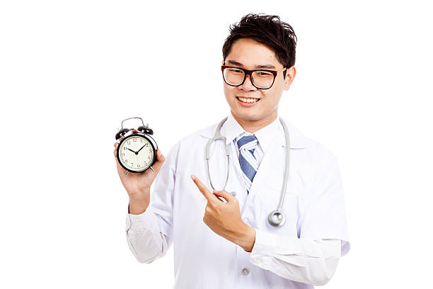 istock Asian male doctor smile point to a clock 523211981