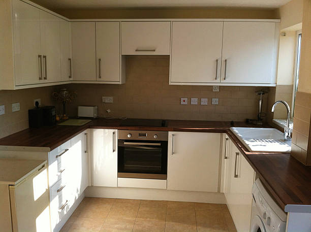 istock Modern kitchen with white glossy cabinets, cooker, sink, wooden worktops 523212597