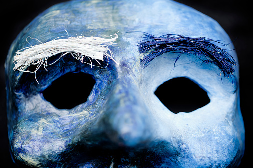 Close up of blue homemade mask with black background.