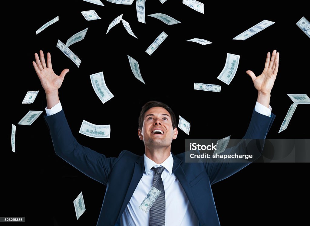 It's raining money! Studio shot of a handsome young businessman surrounded by falling money Abundance Stock Photo
