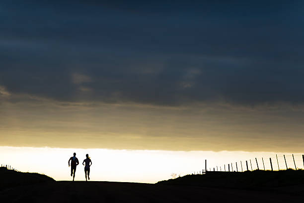 Couple running outdoors at sunrise on a dirt road in the countryside.