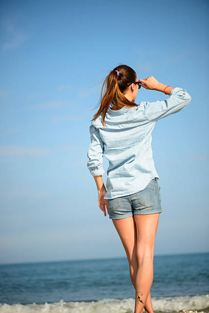 Full length rear view of a young woman looking at the sea