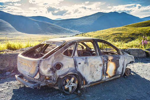 Burned car on the mountain road, sky