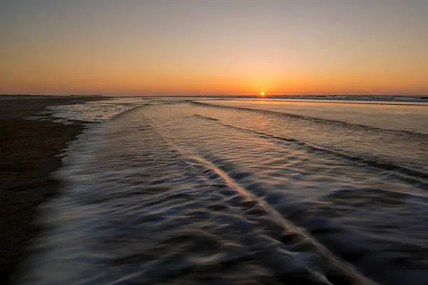 Movement of waves on the beach at sunset on the island of Terschelling in the Netherlands