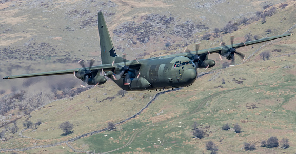Machynlleth, UK - April 20, 2016: a Lockheed-Martin C-130 Hercules transport aircraft of the UK's Royal Air Force pictured flying at low altitude over an area of Wales known as the 'Mach Loop'.