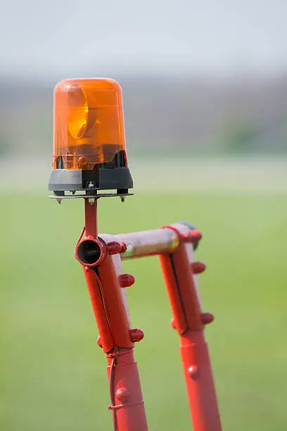 Orange flashing light on a cell red metal scaffolding.