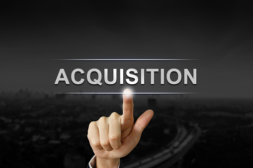 business hand clicking acquisition button on black blurred background