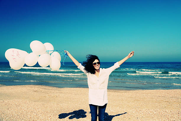 istock woman holding white balloons on seaside 523260180