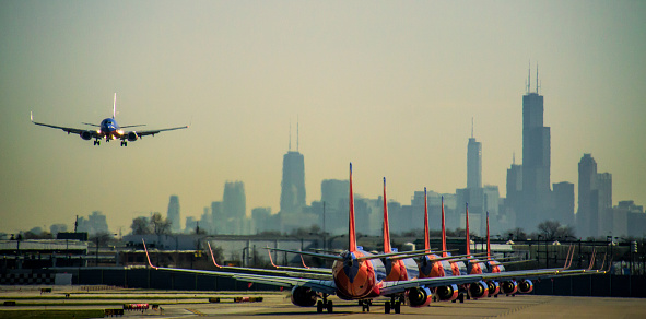 Chicago, IL, USA - April 22, 2013: Chicago Midway International Airport. six Southwest Airlines Boeing 737's are in line for takeoff and one is on final approach to land.  The Chicago skyline in the background.