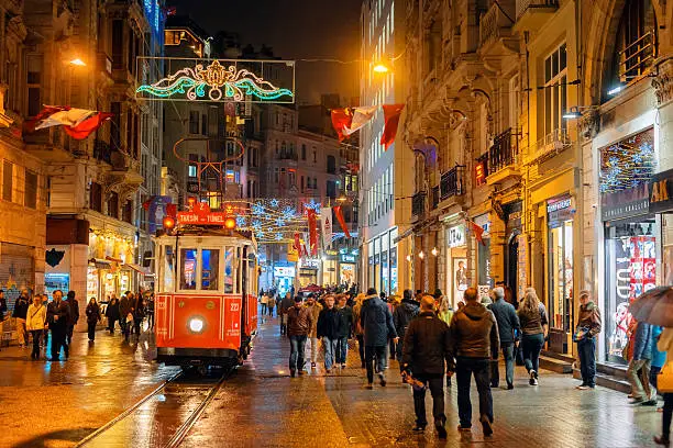Illuminated Tramway on a rainy Istiklal Avenue (Independence Avenue), Lots of national flags for the Republic Day. iStockalypse.