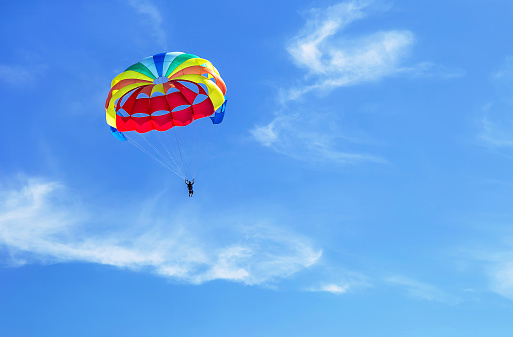 Parachute jumping. Colorful parachute is in the sky, under the clouds. Copy space. Empty place for message. Outdoor. Travel, freedom, adventure, success, business concept.