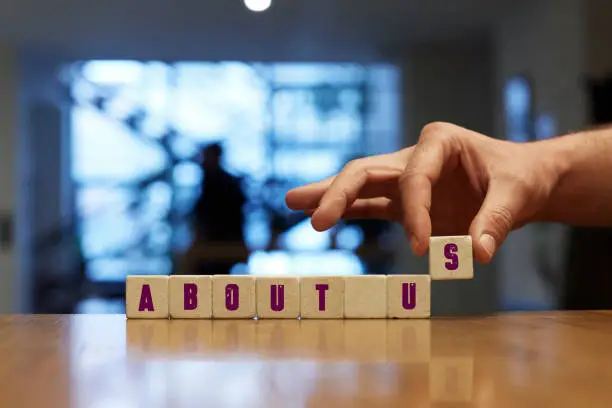 About Us Concept , Hand with alphabet blocks on wooden table