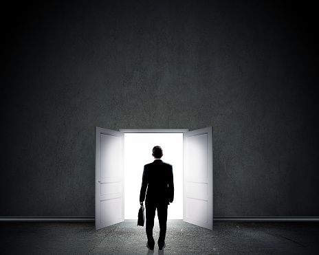 Silhouette of businessman with briefcase standing in doorway