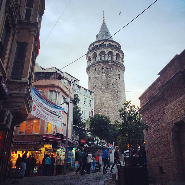 Istanbul, Turkey  - October 26, 2014: Galata Tower in the evening. People walking on famous Istiklal Avenue, shopping.