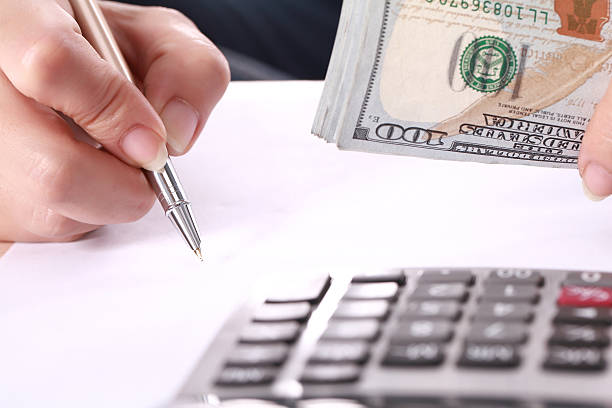 Close-up of a person with money and pen calculating finance.