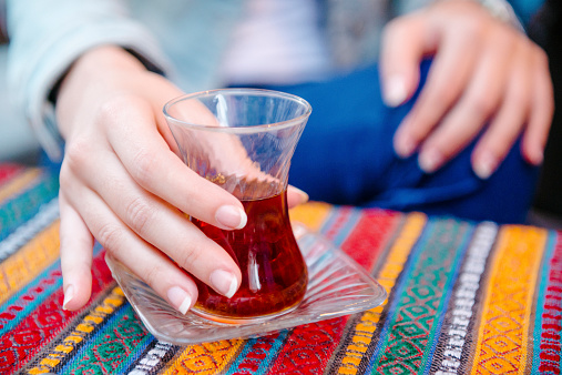 Close up of female hand holding a glass of traditional Turkish tea in cafe in Istanbul, Turkey. Middle East.