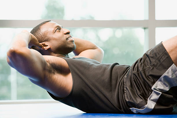mann macht sit-ups im fitnessstudio - people effort waist up african ethnicity stock-fotos und bilder