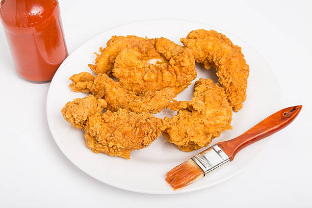 チキンストリップにホワイトのプレートとホットソースとブラシ - chicken tender ストックフォトと画像