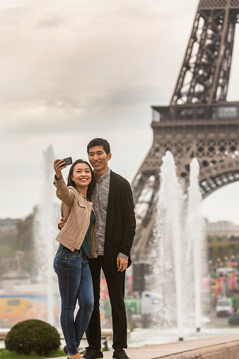 Romantic Asian couple taking a selfie while on vacation in Paris, France