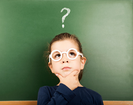 thinking little student in front of the blackboard with question mark