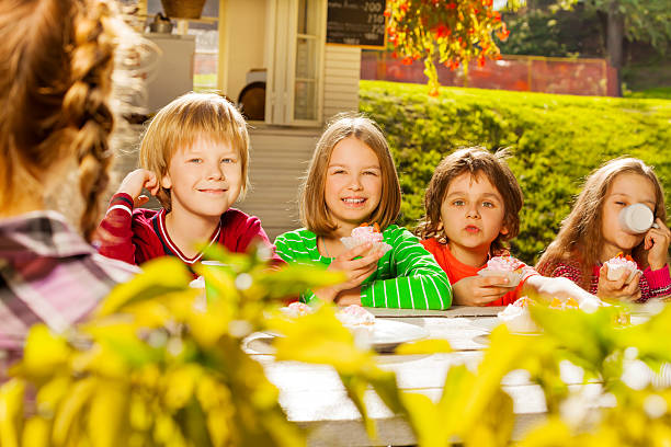 istock Happy children sit at wooden table drinking tea 523293135