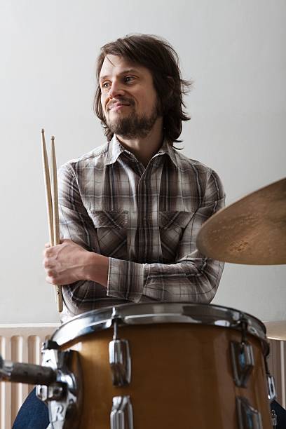 istock Young man holding drumsticks with arms crossed near drumset 523293605