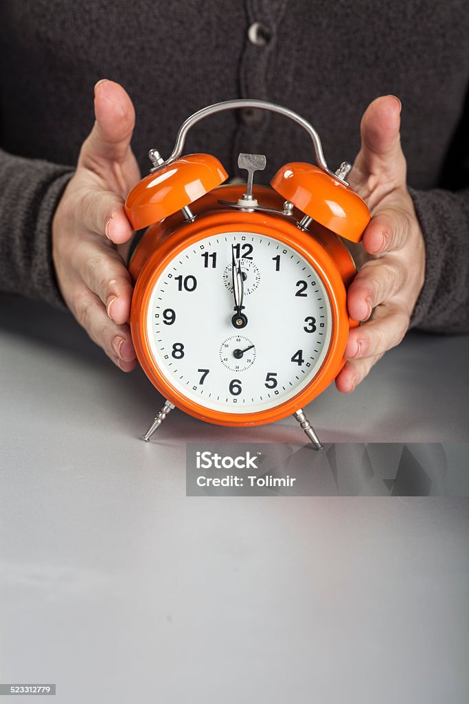 Time Clock in businesswoman hand on table 12 O'Clock Stock Photo