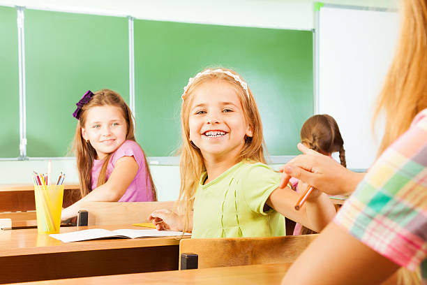 istock Desk row with smiling girls turned and looking 523313271