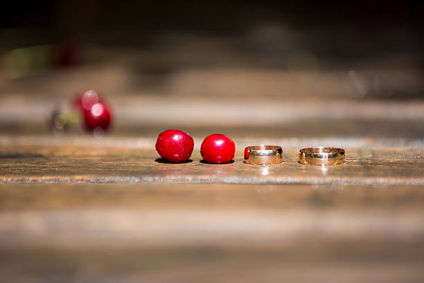 Wedding rings on a wooden bridge and red cherries