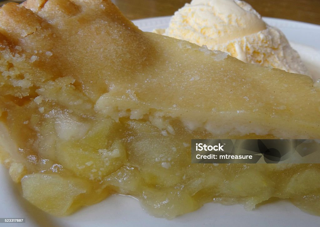 Homemade Bramley apple pie / ice cream dessert, apple tart slice Photo showing a slice of homemade Bramley apple pie and vanilla ice cream.  This apple tart has just been baked and is still hot, being served up on a white plate as a refreshing fruit based dessert / pudding, at the end of a meal / roast Sunday dinner. Apple - Fruit Stock Photo