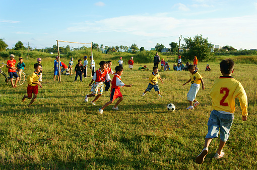Binh Thuan, Viet Nam- October 25, 2014: Group of Asian kid playing football in team, Vietnamese little boy run on grass, outdoor activity of children physical education at countryside, Viet Nam, Oct 26, 2014