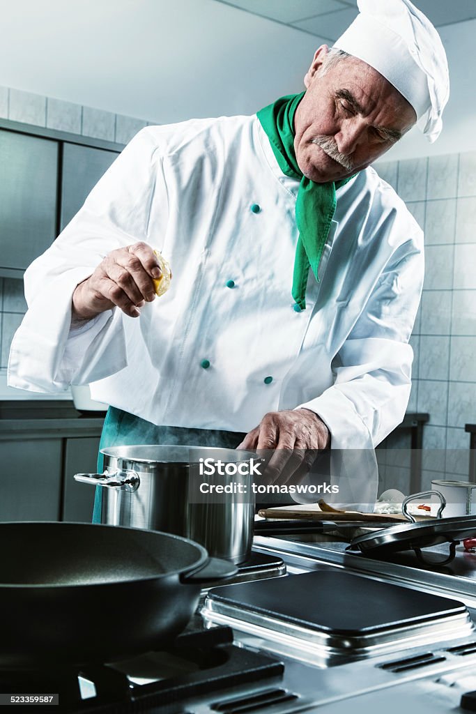 cook squeezing lemon while preparing sauce Professional cook squeezing lemon while preparing sauce Chef Stock Photo