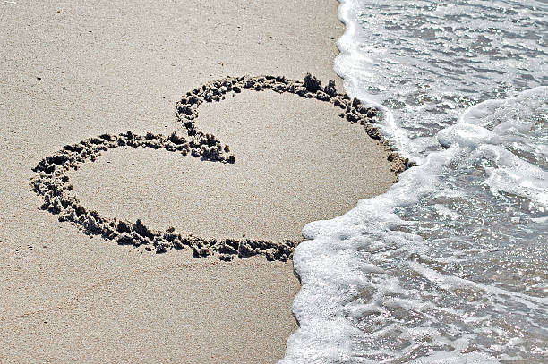 istock Heart drawn in the sand with seafoam and wave 523360823