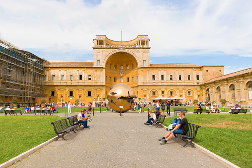 Vatican city, Vatican - September 22, 2014:  Tourists walk in the Courtyard of the Pine Cone in Vatican Museums. The Metal globe statue in the courtyard of pine cone.