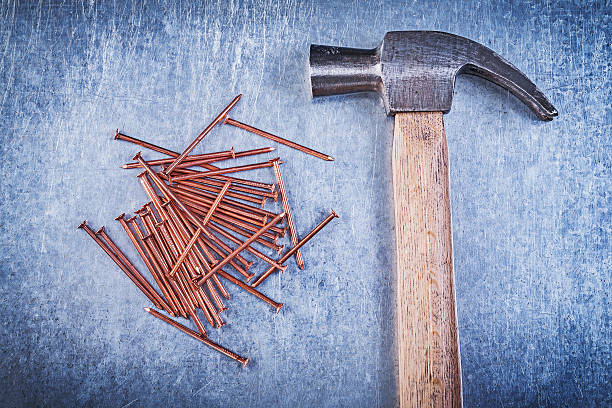 istock Vintage claw hammer copper construction nails on metallic backgr 523377956