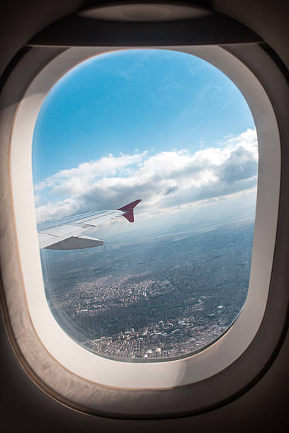 istock Plane wing appears over the city between white clouds 523379371