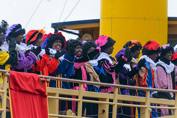 Zwarte Pieten (black pete) on deck of the steamboat Kampen, The Netherlands - November 15, 2014: Sinterklaas and his Black Petes arriving on his steamboat in the city of Kampen, The Netherlands. Sinterklaas and his black helpers are waving to the children who are waiting for the old bishop to arrive. zwarte piet stock pictures, royalty-free photos & images