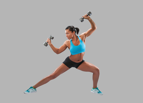 Fit African-American Woman lifting weights, isolated against a studio background