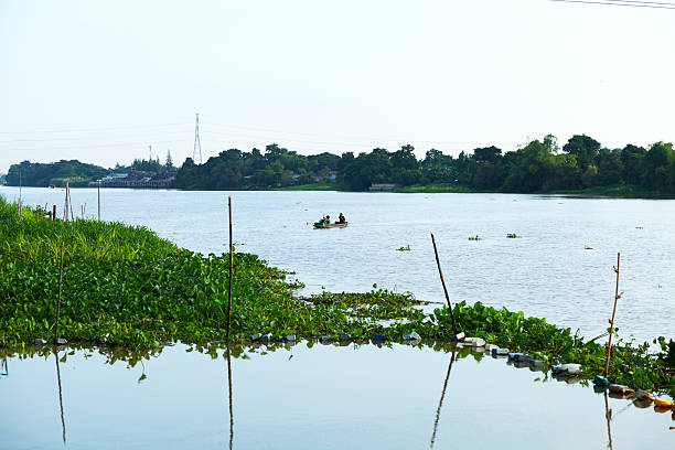 Ayutthaya, Thailand - November 9, 2014: View along river Chao Praya in outskirts of Ayutthaya. On river is a small boat with Thai adult couple. Southern area of Ayutthaya. Morning shot.