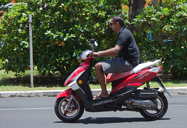 Lisbon, Portugal, July 30, 2025, Motorcyclist wearing helmet riding modern red scooter on urban asphalt road