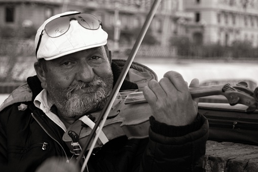 Naples, Italy - November 20, 2006: A gipsy senior  man plays violin as street artist nearby Castel dell'Ovo at Naples.