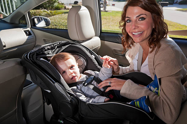 Mother with baby in car seat Young mother (20s) with baby boy (8 months) strapped in a car seat. They are looking at the camera, smiling. Sc0601 stock pictures, royalty-free photos & images