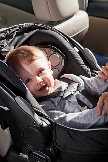 Baby in car seat Baby (8 months) strapped into a rear-facing car seat, in the back seat. He is smiling at the camera. Sc0601 stock pictures, royalty-free photos & images