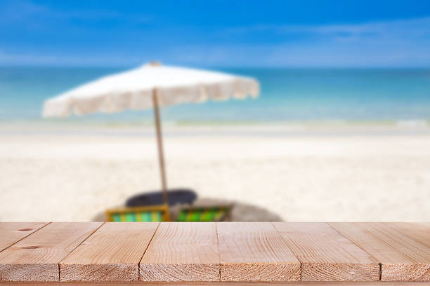 istock Wood table top on blurred blue sea and sand beach 523389618